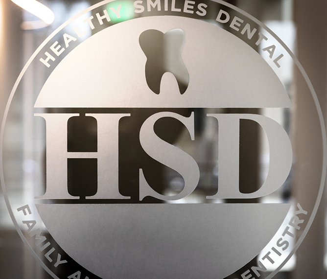 The Healthy Smiles Dental logo on a glass door