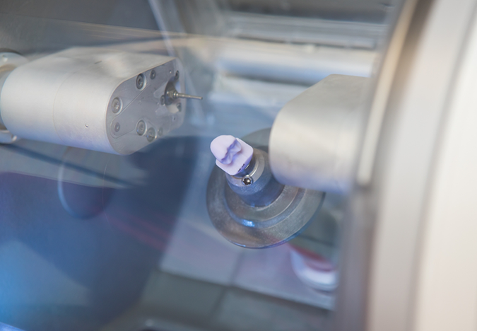 Milling machine creating a dental crown from a ceramic block