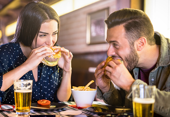 Man and woman eating burgers at a restaurant