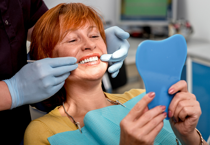 Woman in the dental chair admiring her smile in a mirror