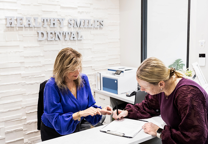 Dental office receptionist helping a patient fill out a form