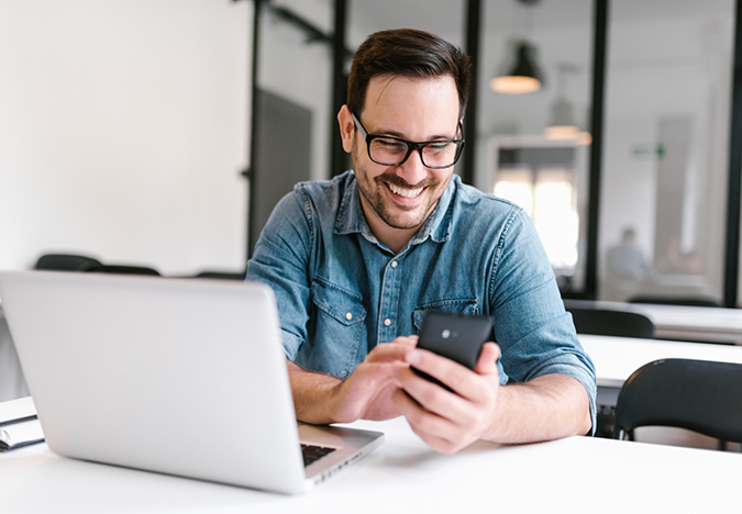Smiling man sitting at a desk with a laptop