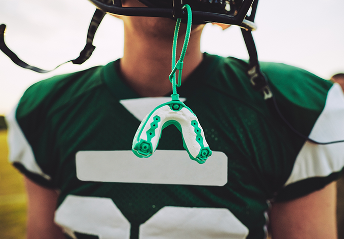 Football player with a mouthguard hanging from their helmet