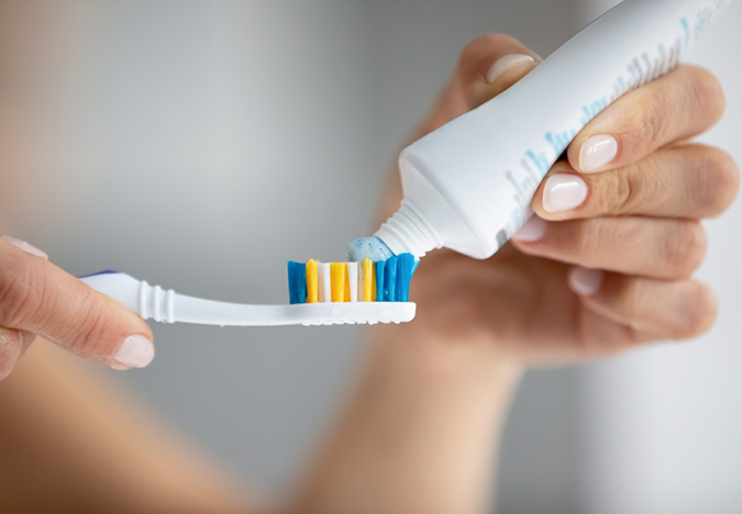 Person putting toothpaste on a toothbrush
