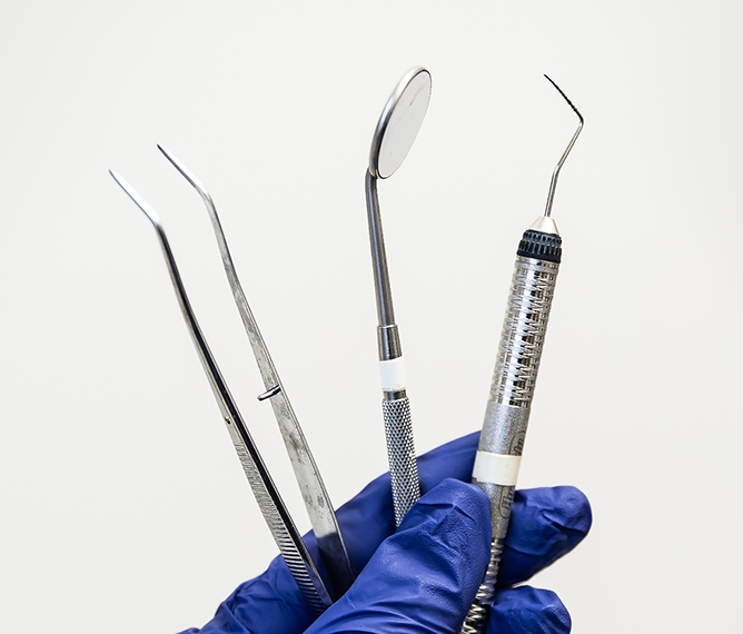 Gloved hand holding dental instruments