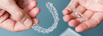 Hands holding two clear aligners
