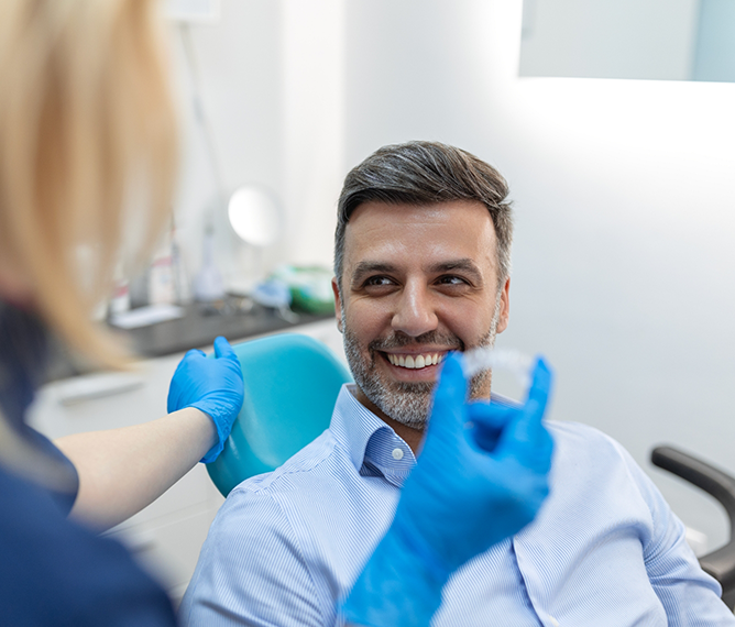 Dentist showing a clear aligner to a patient