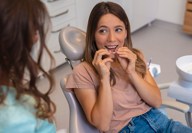 Woman in the dental chair trying on clear aligners